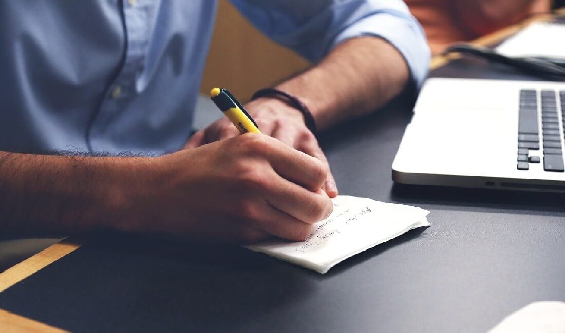 Hände mit Stift und Computer